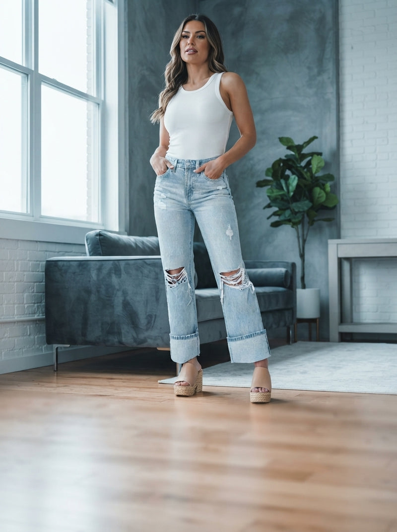 A woman wearing distressed high-waist jeans standing in a bright modern loft space.