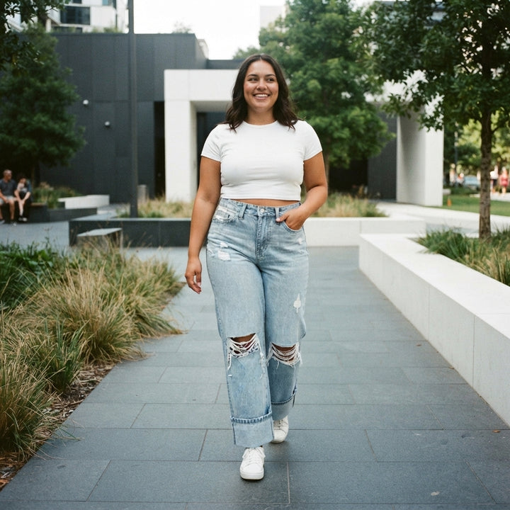 A woman wearing distressed high-waist jeans walking through an urban park, captured in a candid, authentic lifestyle shot.